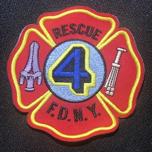 Könnte beinhalten: Roter und gelber gestickter Aufnäher mit weißem Hintergrund. Der Aufnäher zeigt einen vierzackigen Stern mit der Zahl "4" in Blau darin. Die Worte "RESCUE" und "F.D.N.Y." sind ebenfalls auf dem Aufnäher gestickt.