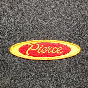 May include: A gold oval-shaped patch with a red background and the word "Pierce" embroidered in yellow.