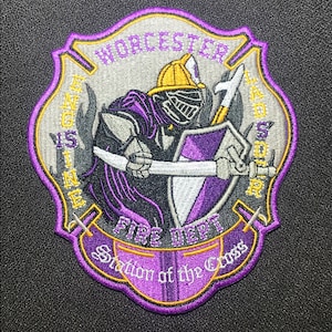 May include: Purple and gold embroidered patch with a knight holding a sword and axe. The patch says "Worcester Fire Dept. Station of the Cross" and "Engine 15 Ladder 50".