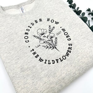 May include: Gray sweatshirt with a black graphic design that says "Consider how many grow the wildflowers. Luke 12:27"