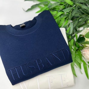 May include: Two sweatshirts, one navy blue and one white, with the words "HUSBAND" and "WIFE" embroidered on them.