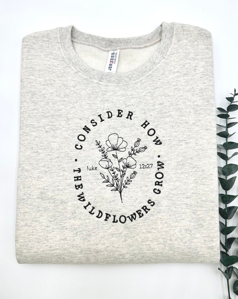 May include: Gray sweatshirt with a black circle design featuring a floral illustration and the text "Consider how the wildflowers grow. Luke 12:27"