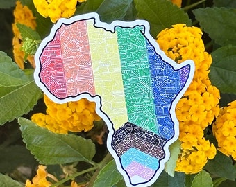 Può includere: Un adesivo del continente africano con un motivo arcobaleno e intricati disegni geometrici. L'adesivo è su uno sfondo di fiori gialli.