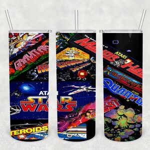 May include: Three 20 oz. stainless steel tumblers with a black base and a clear lid. Each tumbler features a different design of classic Atari video game graphics, including Star Wars, Asteroids, and Missile Command.