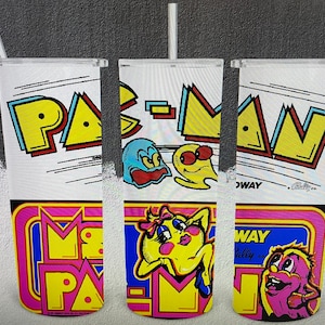 May include: Three white tumblers with a Pac-Man theme. The tumblers feature a yellow Pac-Man character with a pink ghost and blue ghost. The bottom of the tumblers feature a pink and yellow Pac-Man logo with the text "Midway" and "Rally Co."