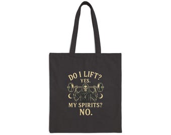 May include: Black tote bag with a graphic featuring a grim reaper lifting weights. The text reads "DO I LIFT? YES. MY SPIRITS? NO." The design includes a barbell and crescent moons. The bag has long handles.