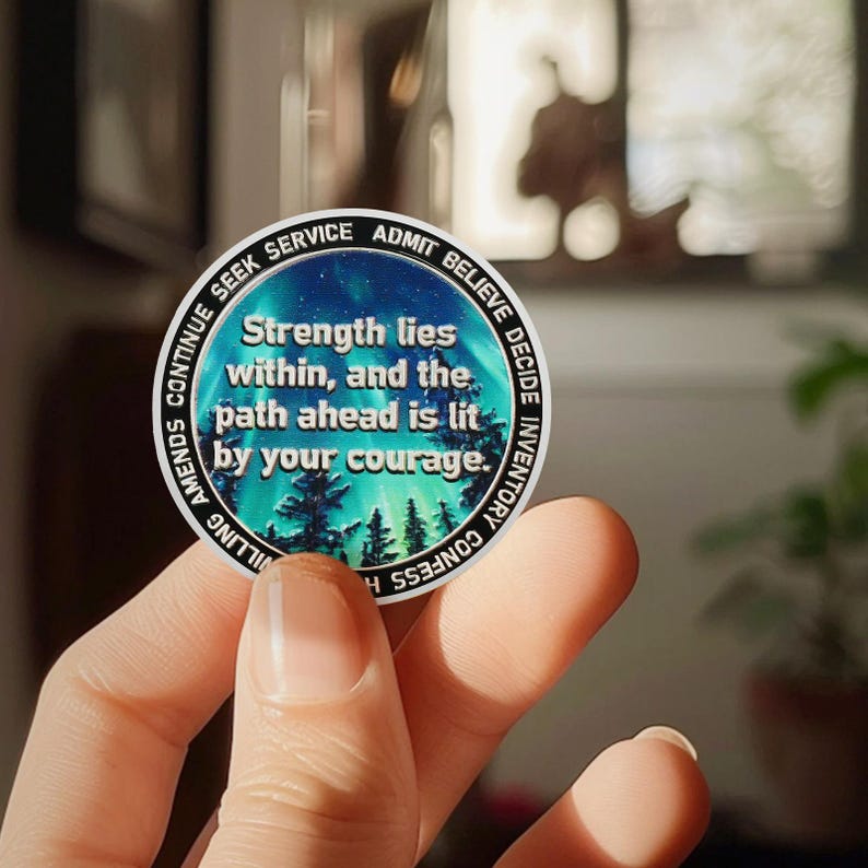 May include: A silver round coin with a blue, green, and white design. The coin has the words "Strength lies within, and the path ahead is lit by your courage." around the edge.