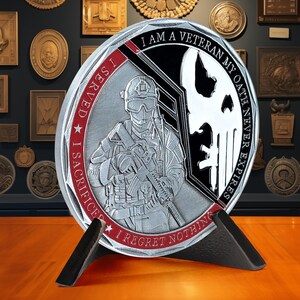 May include: A silver and black round challenge coin with a red and white border. The coin features a soldier holding a rifle, a skull, and the text "I AM A VETERAN MY OATH NEVER EXPIRES I SERVED I SACRIFICE I REGRET NOTHING".