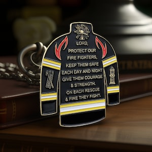 May include: A black and gold metal keychain shaped like a firefighter's jacket with a red and yellow stripe design. The keychain has a chain and a ring. The keychain has the text "LORD, PROTECT OUR FIRE FIGHTERS, KEEP THEM SAFE EACH DAY AND NIGHT GIVE THEM COURAGE & STRENGTH. ON EACH RESCUE & FIRE THEY FIGHT."