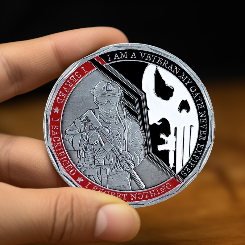 May include: A silver challenge coin with a red and black design. The coin features a soldier holding a rifle, a skull, and the text "I am a veteran, my oath never expires. I sacrificed, I served, I regret nothing."
