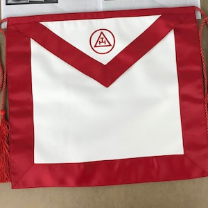 May include: White Masonic apron with a red border and a red tassel. The apron has a white embroidered symbol of a triangle with a letter 'G' inside.