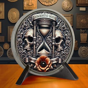 Op de afbeelding: Een ronde zilveren munt met een sierlijk ontwerp met twee schedels, een zandloper en een klaproos. De munt is gegraveerd met de woorden "Memento Mori".