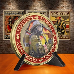 May include: A gold-coloured challenge coin featuring a firefighter in a helmet and gas mask standing in front of a red and yellow fire. The coin is inscribed with the words "Community Tradition Sacrifice Dedication" around the edge.