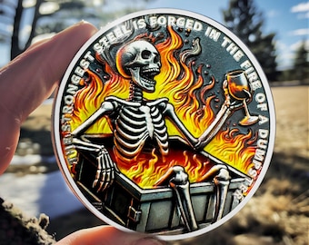 May include: A silver round coin with a black skeleton sitting in a dumpster fire. The skeleton is holding a glass of wine. The coin has the text "The strongest steel is forged in the fire of a dumpster" around the edge.