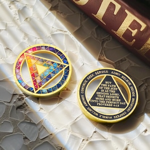 Puede incluir: Dos medallones circulares dorados. Uno presenta un dise&ntilde;o geom&eacute;trico colorido con un tri&aacute;ngulo en el centro. El otro tiene el texto "Pero el camino de los justos es como la luz brillante..." y otras frases.