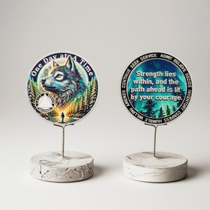 May include: Two round, white, marble-like bases with metal stands holding two round, colorful, printed discs. The left disc has a wolf howling at the moon with the text "One Day at A Time". The right disc has a blue and green background with the text "Strength lies within, and the path ahead is lit by your courage."