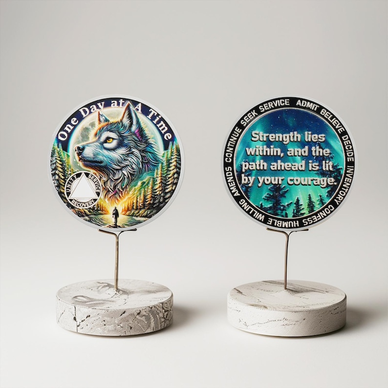 May include: Two round, white, marble-like bases with metal stands holding two round, colorful, printed discs. The left disc has a wolf howling at the moon with the text "One Day at A Time". The right disc has a blue and green background with the text "Strength lies within, and the path ahead is lit by your courage."