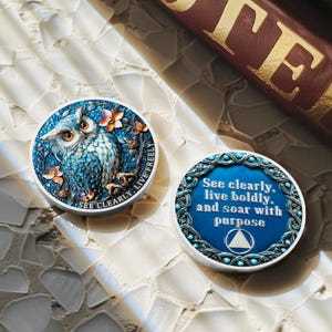 May include: Two round, decorative owl-themed objects. One features a blue owl with floral accents and the text "SEE CLEARLY. LIVE FREELY." The other has the text "See clearly, live boldly, and soar with purpose."