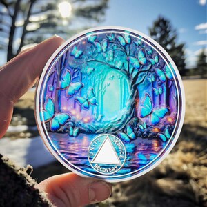 Könnte beinhalten: Eine runde Silbermünze mit einem blauen und violetten, irisierenden Finish. Die Münze zeigt ein Design eines Waldes mit Schmetterlingen und einem Dreieck mit den Worten "Einheit", "Dienst" und "Wiederherstellung" eingraviert.