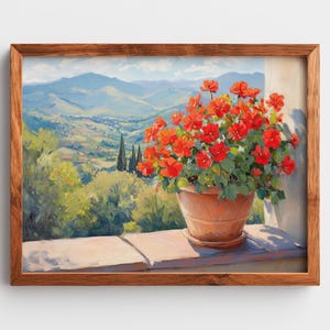May include: A framed painting of a terracotta pot filled with vibrant red flowers. The pot sits on a stone ledge, with a scenic view of rolling green hills and blue mountains in the background. The artwork is framed in a warm brown wood.