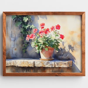 May include: Watercolor painting of a terracotta pot filled with red geraniums and green foliage. The pot sits on a stone ledge with a climbing vine. The artwork is framed in a wooden frame, capturing a sunny outdoor scene.