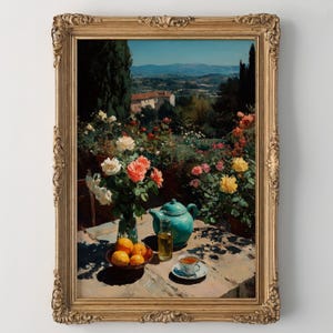 Könnte beinhalten: Gerahmtes Gemälde, das eine ruhige Szene im Freien zeigt. Auf einem Tisch stehen eine türkisfarbene Teekanne, eine Glasflasche, eine Teetasse und eine Schüssel mit Orangen. Eine Vase mit Rosen steht daneben. Der Hintergrund zeigt einen Garten und eine ferne Landschaft.