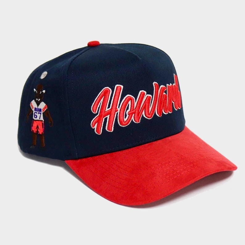 May include: Navy blue and red baseball cap with the word "Howard" in red script. The cap features a red brim and a small embroidered figure on the side.