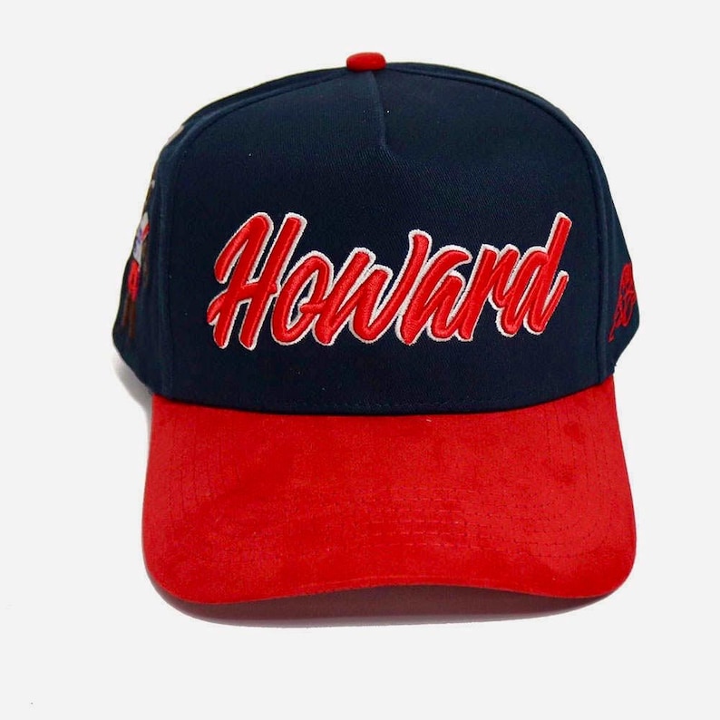 May include: A navy blue and red baseball cap with the name "Howard" embroidered in red script across the front. The cap has a red brim and a red button on top. The cap is a classic style.