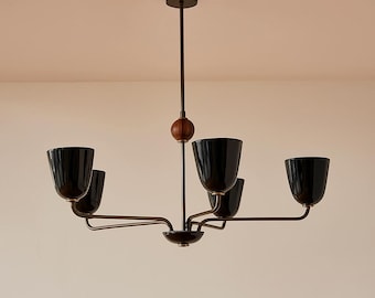 May include: A modern chandelier with five black, bell-shaped shades. The fixture has a dark bronze finish with a wooden accent. The light hangs from a central rod and has curved arms extending to hold the shades.