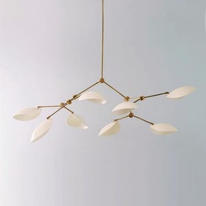 Puede incluir: Una lámpara de araña moderna con acabado de latón y pantallas blancas en forma de hoja. La lámpara tiene múltiples brazos que se extienden desde un punto central, cada uno con una pantalla. El diseño recuerda a una rama de árbol.