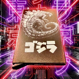 May include: A brown box featuring a white Godzilla illustration and Japanese text. The box is set against a neon-lit cityscape background with red and purple accents, creating a vibrant and dynamic visual.