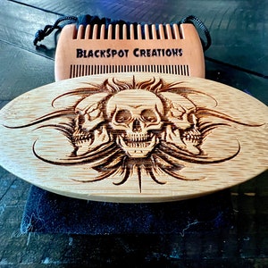 May include: A wooden beard comb with a skull design. The comb is engraved with three skulls and flames. The comb is made by Blackspot Creations.