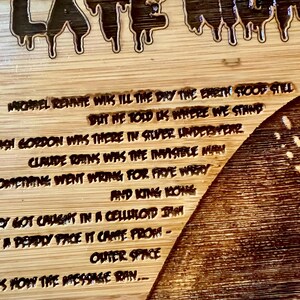 May include: A wooden cutting board with engraved text and a decorative design. The text includes phrases like "Late Night" and lines from a poem. The board has a natural wood grain.