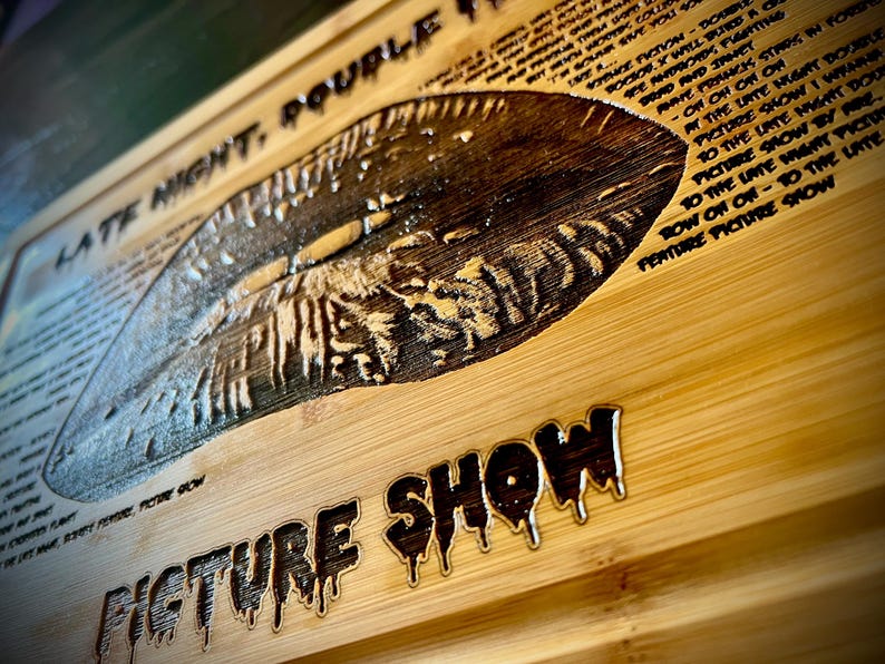 May include: Wooden sign with the words "LATE NIGHT, DOUBLE FEATURE PICTURE SHOW" carved into the wood. The sign has a vintage, horror movie theme with dripping font and a detailed image.