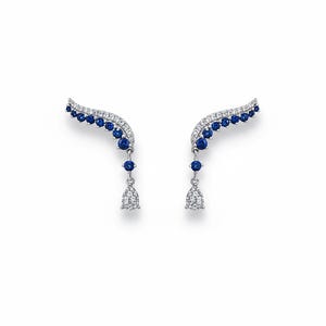 Pair of blue sapphire and diamond-style leaf ear climber earrings on a pure white background. The earrings feature a silver vine design set with round blue gemstones and a teardrop-shaped clear stone dangling at the bottom. Realistic soft drop shadows included.