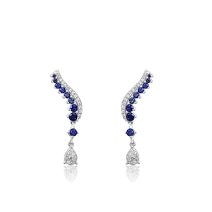 Puede incluir: Un par de pendientes plateados con un dise&ntilde;o curvo. Los pendientes presentan una serie de peque&ntilde;as piedras preciosas redondas de color azul oscuro y piedras claras y brillantes. Cada pendiente tiene un colgante en forma de l&aacute;grima en la parte inferior.