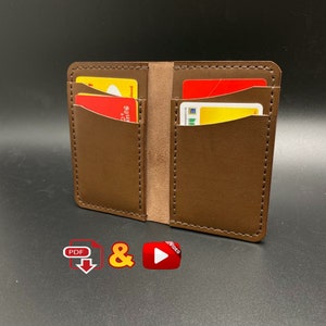 May include: A brown leather wallet with two card slots. The wallet is open and has two cards inside.