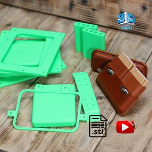 May include: An assortment of 3D-printed green plastic components, including rectangular frames, rectangular blocks with holes, and a rectangular piece with a series of holes. Also, two brown leather cases with metal clasps and a stack of items.