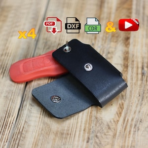 Puede incluir: Un estuche para llavero de cuero negro con cierre de botón plateado, abierto para revelar un interior gris. Una llave de coche roja está al lado del estuche. La imagen incluye iconos para archivos PDF, DXF, CDR, un ampersand y un icono de vídeo.