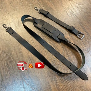 Può includere: Due cinturini in pelle nera con dettagli in argento. I cinturini sono regolabili e hanno una chiusura a fibbia. I cinturini sono per una borsa o altro accessorio.