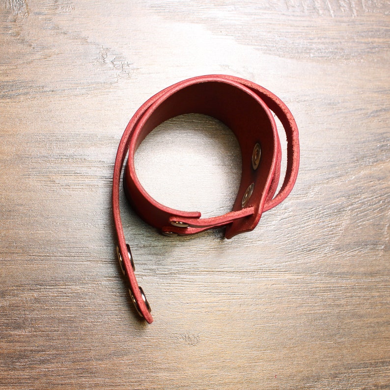 May include: A red leather bracelet with gold-toned metal snaps.