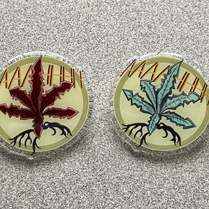 May include: Two round pins with a green and a red plant design. The text "AAAAAHHHH" is printed around the edge of each pin.