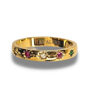 Könnte beinhalten: Ein Goldring mit fünf sternförmigen Fassungen, jede mit einem andersfarbigen Edelstein. Die Edelsteine sind rot, weiß und grün.