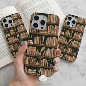 May include: Phone cases with a dark green background and a bookshelf design. The cases feature rows of books in various colors, along with candles, keys, and potion bottles. The cases are held in front of an open book.