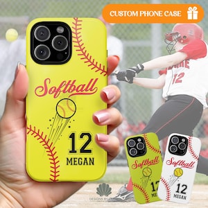 May include: Yellow phone case with a softball design. The case features the word "Softball" in pink script, a softball graphic, the number 12, and the name "Megan" in black. Red stitching detail and a gift box icon are also visible.