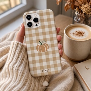 May include: A beige and white gingham patterned phone case featuring a central illustration of a light brown pumpkin with a green stem. The lower portion of the case displays the personalized initials EMJ in a simple, dark brown serif font.