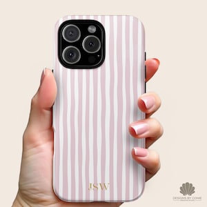May include: A phone case with a pink and white striped pattern. The case has a gold monogram of the initials "JSW" at the bottom. The phone case has a black camera module with three lenses.