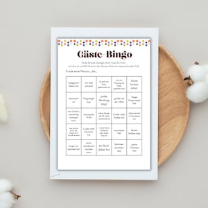 May include: A printable bingo card with a colourful design. The card is titled "G&auml;ste-Bingo" and has a grid of squares with various prompts for finding guests at a party.  The prompts include things like "has gum", "is taller than 1.90m", "has a book", and "likes coffee".