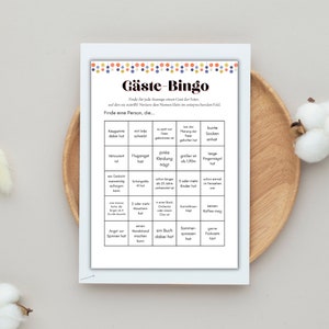 May include: A printable bingo card with a colorful design. The card is titled "G&auml;ste-Bingo" and has a grid of squares with various prompts for finding guests at a party.  The prompts include things like "has gum", "is taller than 1.90m", "has a book", and "likes coffee".