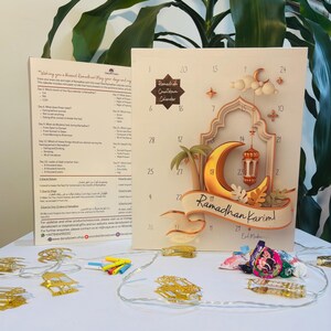 Pu&ograve; includere: Un calendario del conto alla rovescia del Ramadan con una luna crescente dorata, una lanterna e le parole "Ramadhan Karim!". Il calendario ha un design 3D con numeri ed elementi decorativi. Un elenco di domande &egrave; a sinistra.